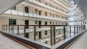 A multi-level interior with a central open space, railings, and a tiled floor. - Modern apartment with skyline and sea views (Cape Town)