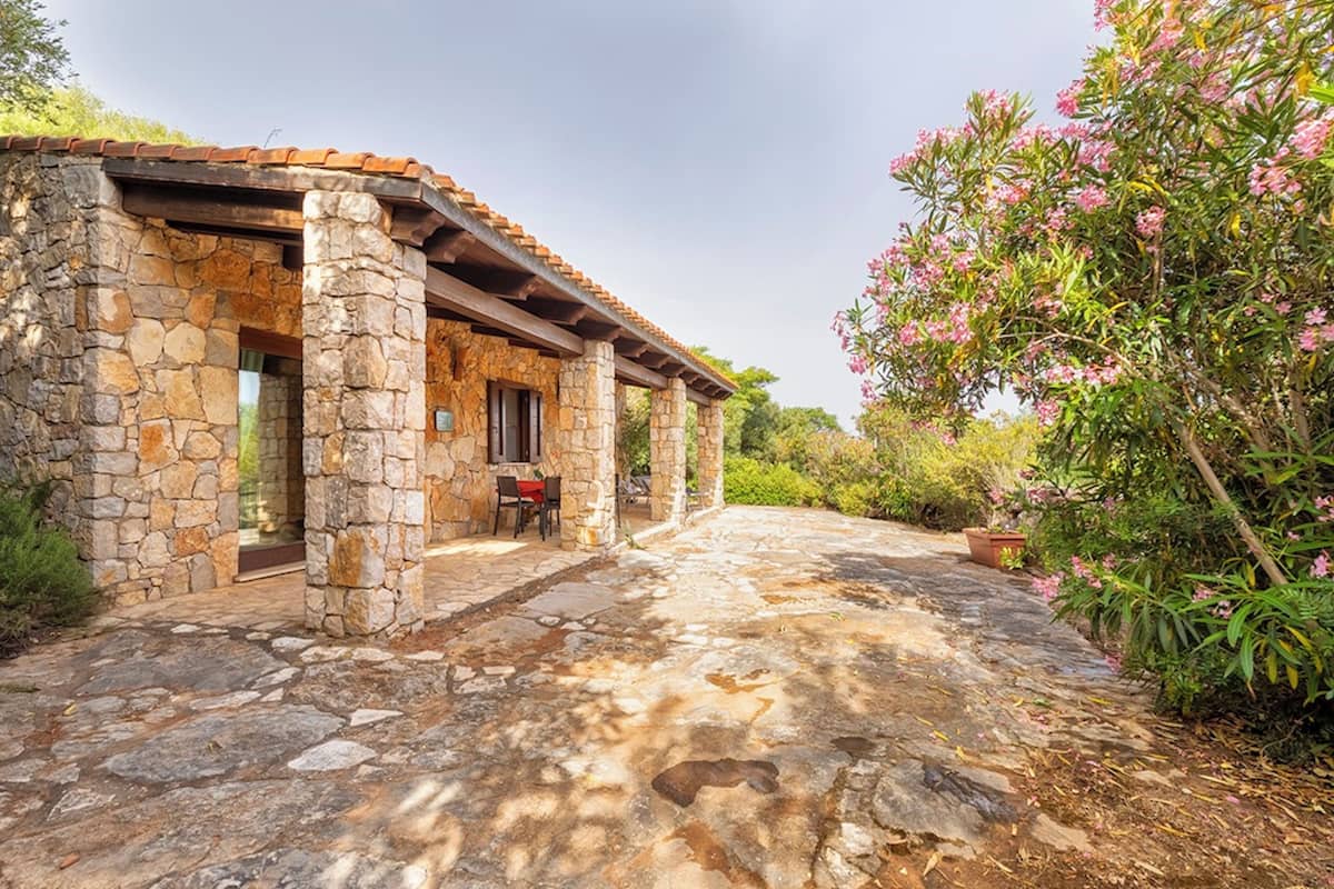 A stone building with a covered patio, a door, and a window.