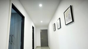 A hallway with a door at the end, a light fixture on the ceiling, and three framed pictures on the wall. - Avaani Residency ,A Spacious 5-bedroom villa in beautiful Jalandhar with AC (Jalandhar)