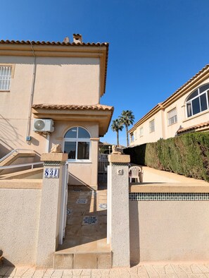 Un edificio residencial con vestíbulo de baldosas, buzón y cielo azul despejado.