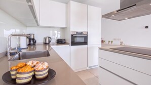 A modern kitchen with white cabinetry, a stainless steel sink, and a countertop with a toaster. - Lotus Jardinana Paradise (Mijas)