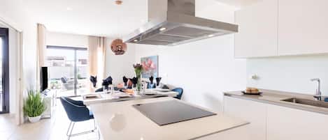 A modern kitchen with a central island, stainless steel appliances, and a view to the living area.
