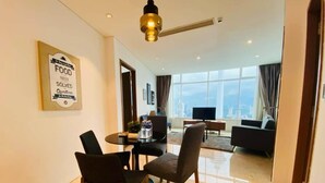 Een moderne woonkamer met een eethoek, een groot raam met uitzicht op de stad en een bord aan de muur.
