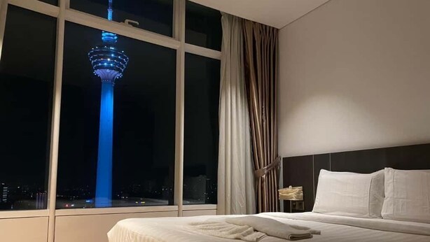 Een hotelkamer met een groot raam, een bed en een ’s nachts zicht op een toren.