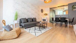 A modern living room with a sofa, coffee table, and dining area. - Ravissante New 3 chambres à Roubaix (Roubaix)