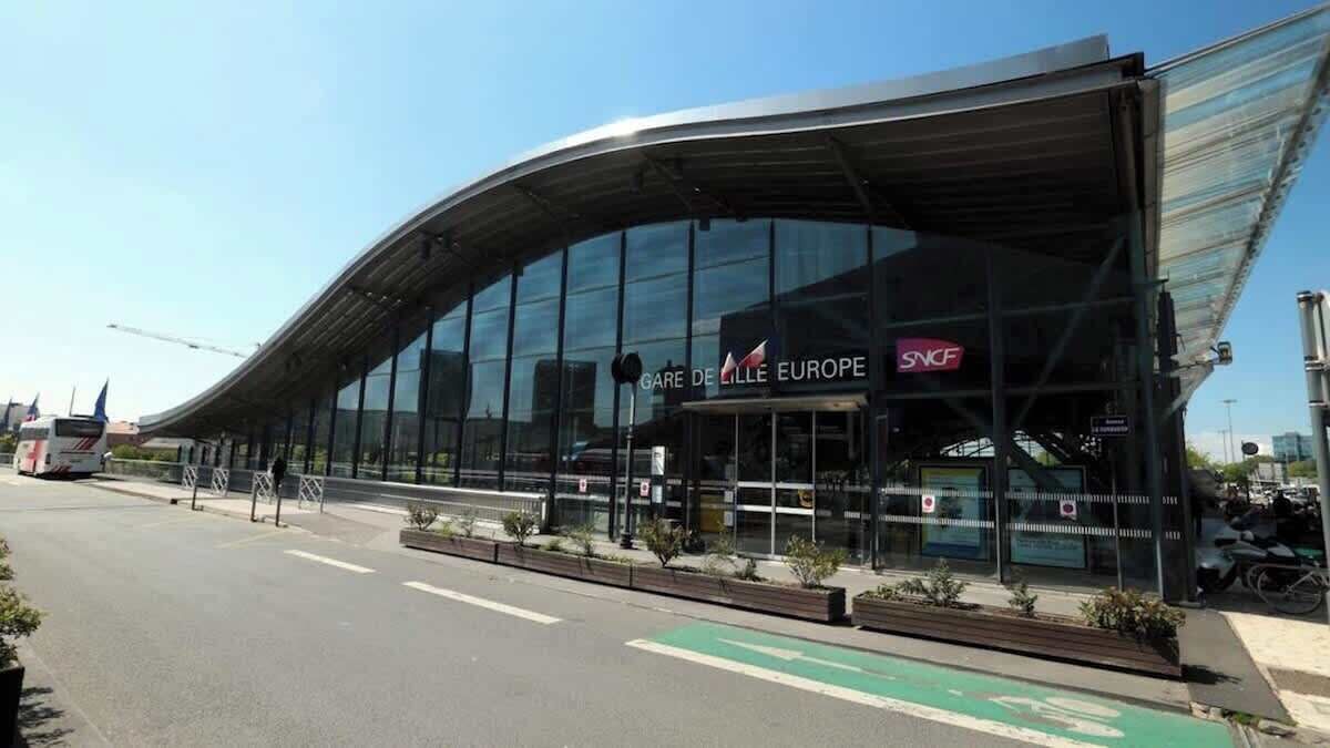 A modern building with a curved glass facade and a sign reading "GARE DE LILLE EUROPE".