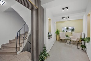 A modern interior with a staircase, seating area, and potted plants. - Exclusive City Apartment—New & Minimalist Design (Bad Kissingen)