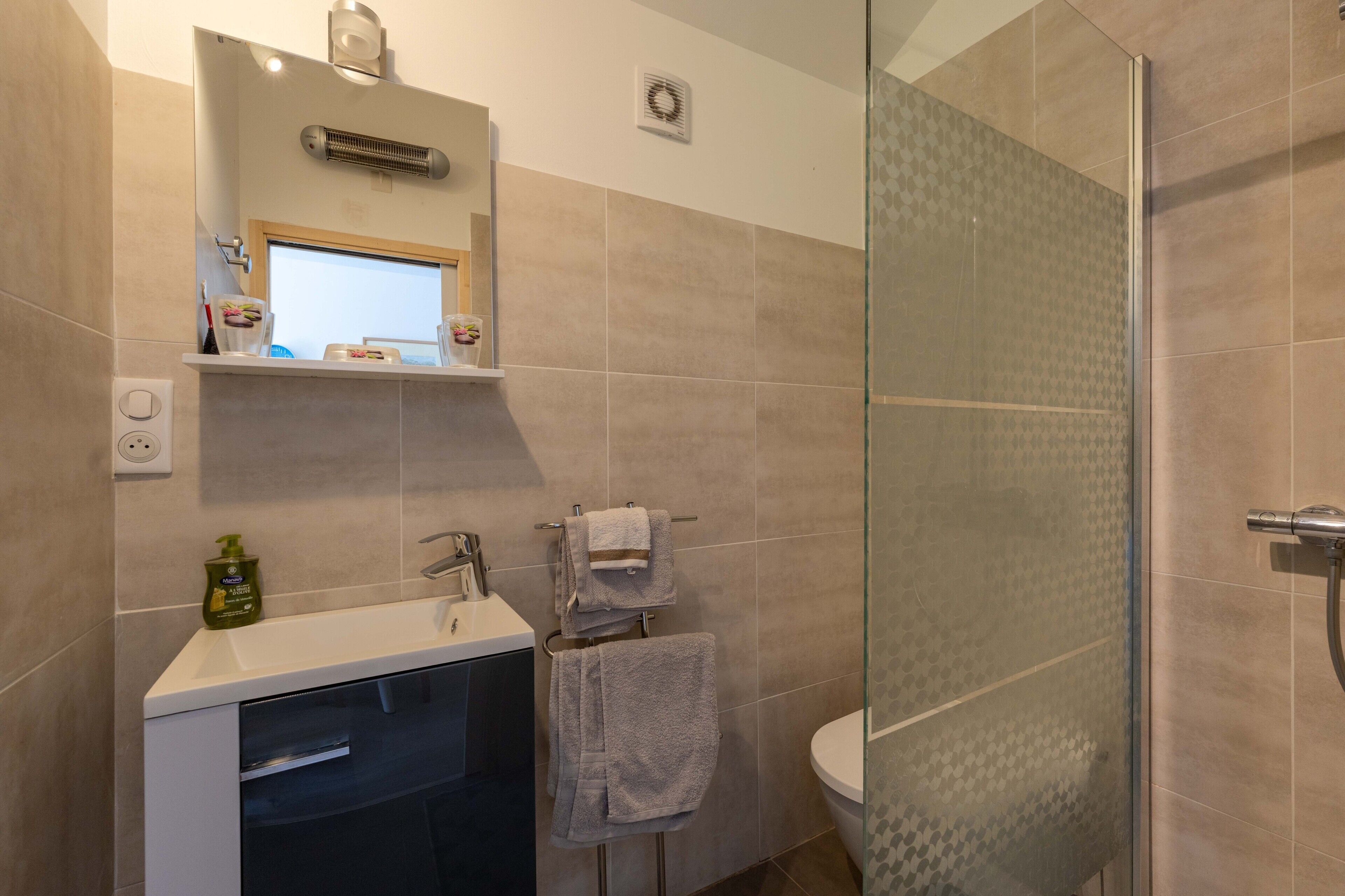 A bathroom with a glass shower enclosure, a sink with a mirror, and a towel rack.