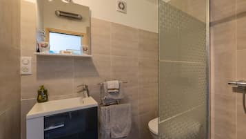 A bathroom with a glass shower enclosure, a sink with a mirror, and a towel rack.