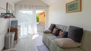 A cozy living room with a sofa, a television, and a window with curtains.