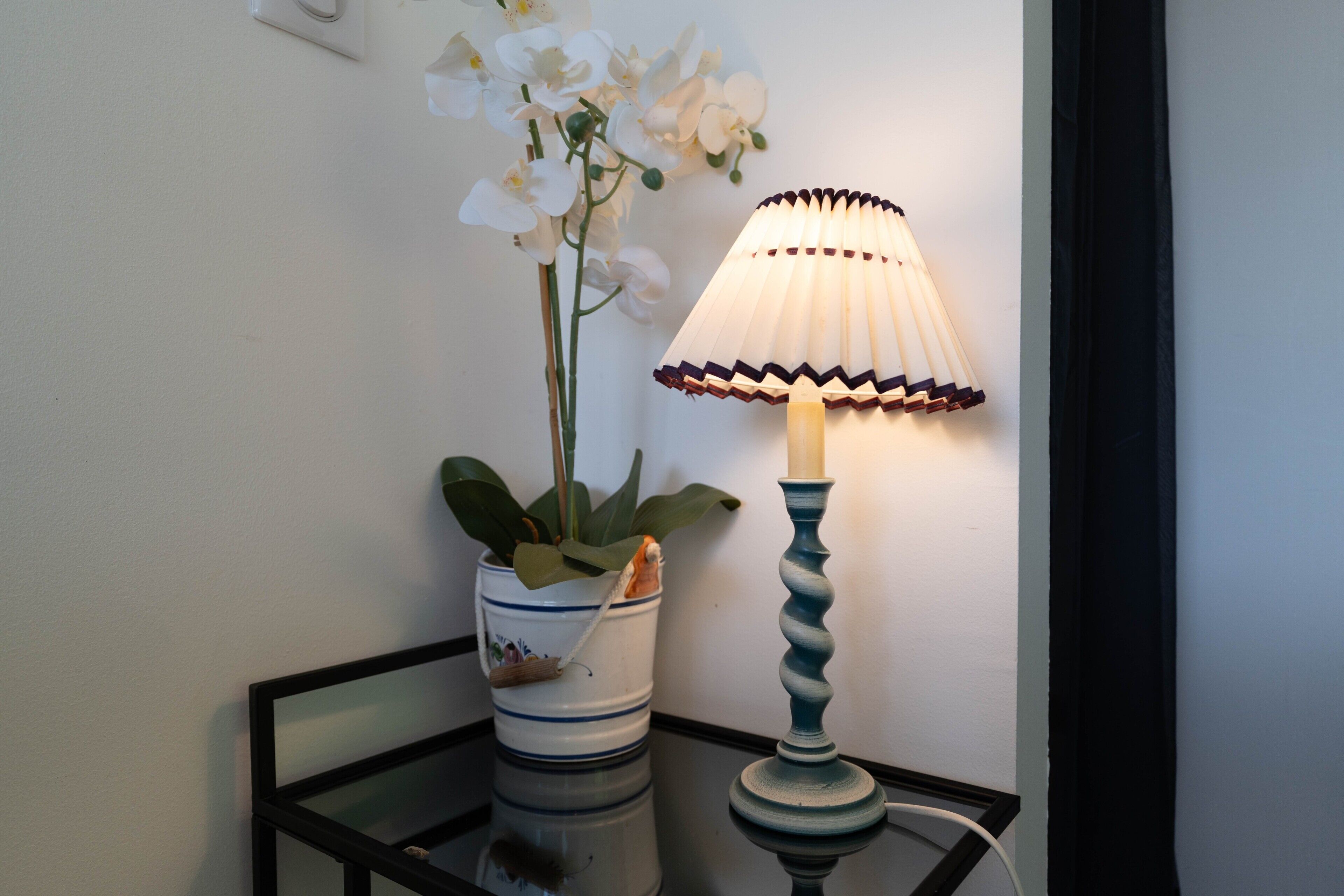 Een tafel met een potorkidee en een lamp met een decoratieve lampenkap.