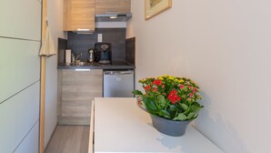 A compact kitchen with wooden cabinets, a coffee machine, and a dishwasher.