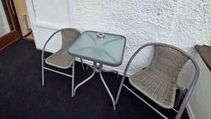 Un'area relax all'aperto con un tavolo in vetro e due sedie in vimini.