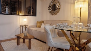 A modern living room with a glass dining table, a sofa, and a coffee table. - Les Nuits en Grands Crus Cosy apartment near Beaune, in the heart of the vineyards  (Ladoix-Serrigny)