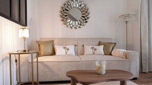 A modern living room with a striped sofa, a round mirror, a side table, and a floor lamp. - Les Nuits en Grands Crus Cosy apartment near Beaune, in the heart of the vineyards  (Ladoix-Serrigny)