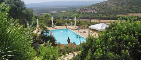 Una piscina al aire libre de temporada, sombrillas