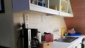 Une cuisine avec des meubles blancs, une machine à café et une petite boîte posée sur le comptoir.