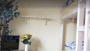 Une chambre avec des lits superposés, une petite table sur laquelle est posé un vase de fleurs et un four à micro-ondes.