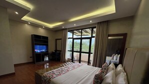 Ein modernes Hotelzimmer mit einem großen Bett, einem Schreibtisch, einem Fernseher und einem Balkon mit Blick.