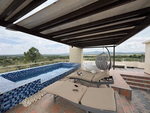 A rooftop terrace with a swimming pool, outdoor seating, and a hanging chair.