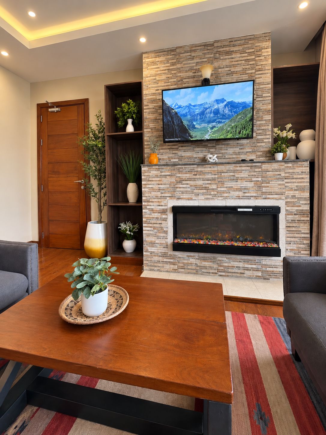 A living room with a fireplace, a television mounted on a stone wall, and a wooden door.