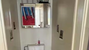 Pieni kylpyhuone, jossa on wc, pesuallas ja peili.