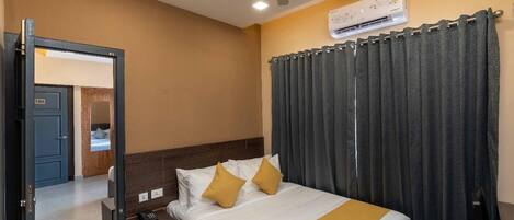 Una habitación de hotel con cama, mesita de noche y un equipo de aire acondicionado.