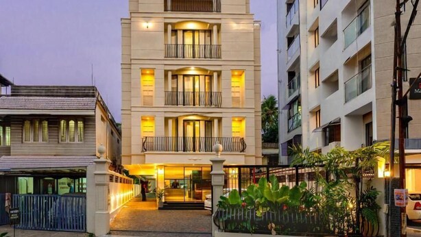 Een meerlaags hotel met een moderne gevel, balkons en een goed verlichte entree.