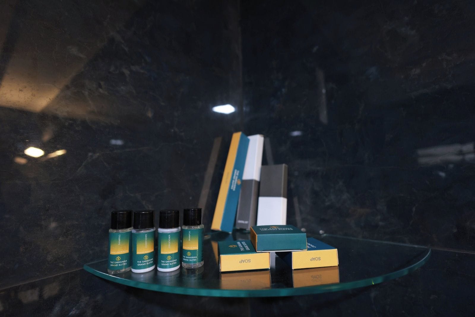 Exposição de suítes de hotel, com garrafas de produtos e alguns livros numa estante de vidro.