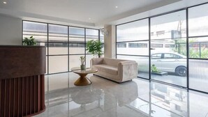 Een moderne lobby met een bank, een bijzettafeltje en grote ramen met uitzicht op de straat.