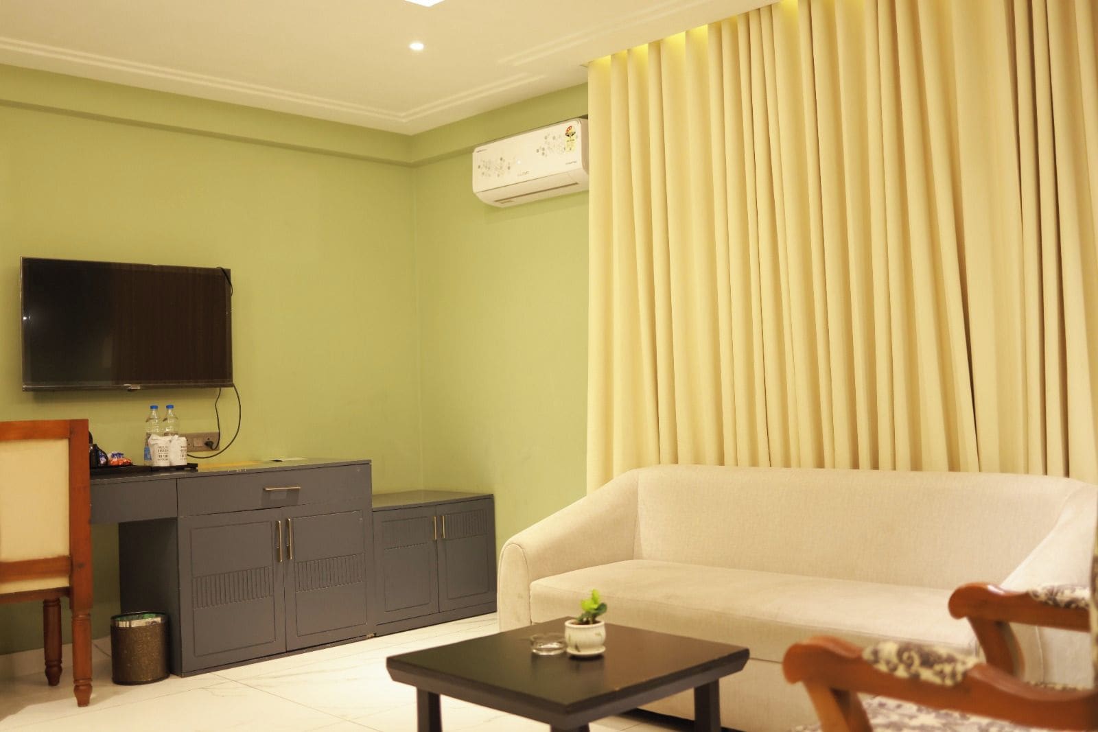 A living room with a sofa, a coffee table, a TV, a cabinet, and a curtain.