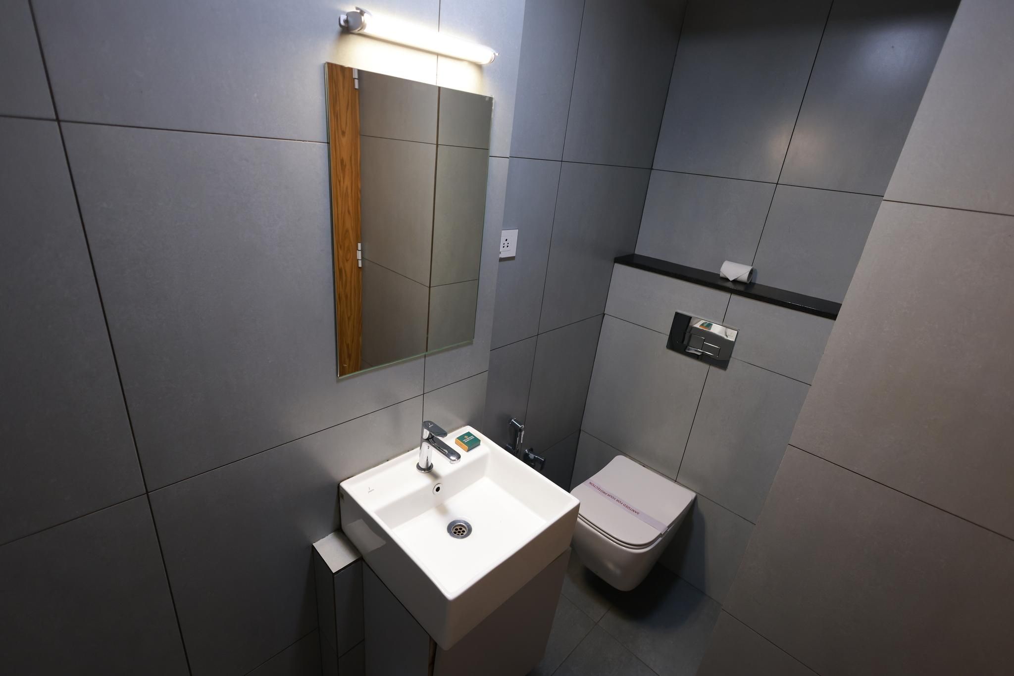 A modern bathroom with a white sink, a mirror, and a toilet.