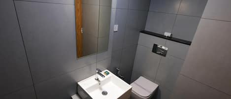 A modern bathroom with a white sink, a mirror, and a toilet.