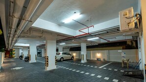 Een parkeergarage met meerdere verdiepingen, zichtbare constructiedragers en een witte auto geparkeerd in het midden.