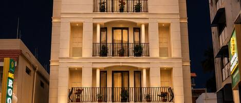 A multi-story hotel with a sign for 'SARAVANA GRAND SUITES' at the entrance.