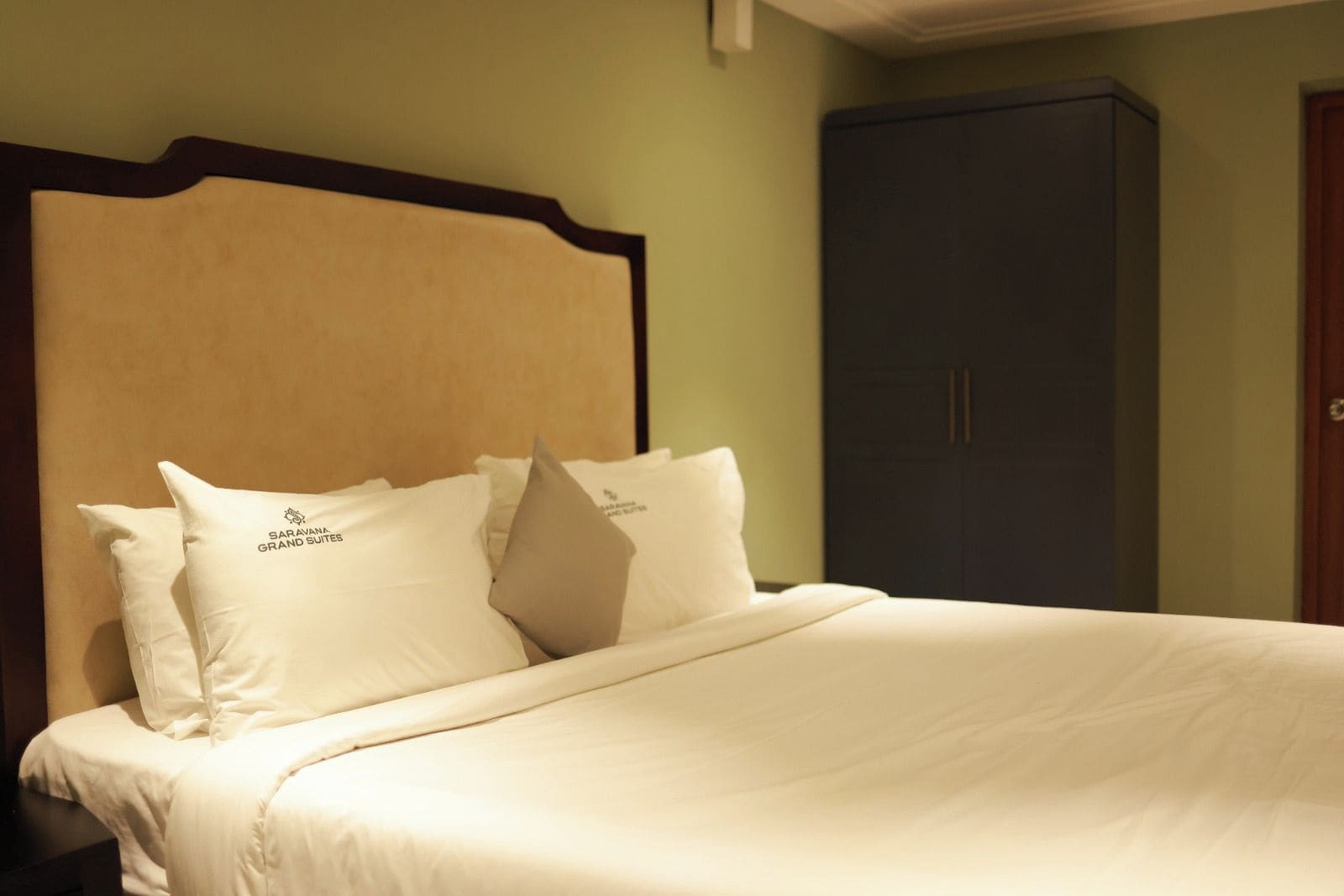 Quarto de hotel com cama, almofadas e um guarda-roupa.