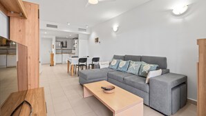 Un salon moderne avec un canapé gris, une table basse en bois et un ventilateur de plafond.