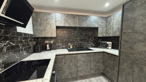 A modern kitchen with dark marble countertops, a built-in microwave, and a sink. - Aurora Apartments (Peterborough)