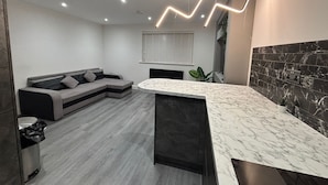 A modern kitchen with a marble countertop, a built-in oven, and a black backsplash. - Aurora Apartments (Peterborough)