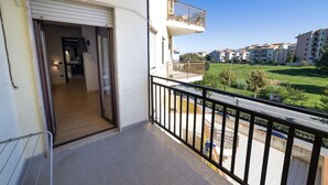 A balcony with a view of a residential area, a door leading to an interior space, and a railing. - House le Treemme - Corigliano Rossano (Corigliano Scalo)