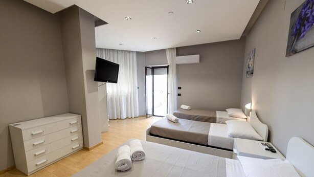 A hotel room with two beds, a flat-screen TV, a dresser, and a window with curtains. - House le Treemme - Corigliano Rossano (Corigliano Scalo)