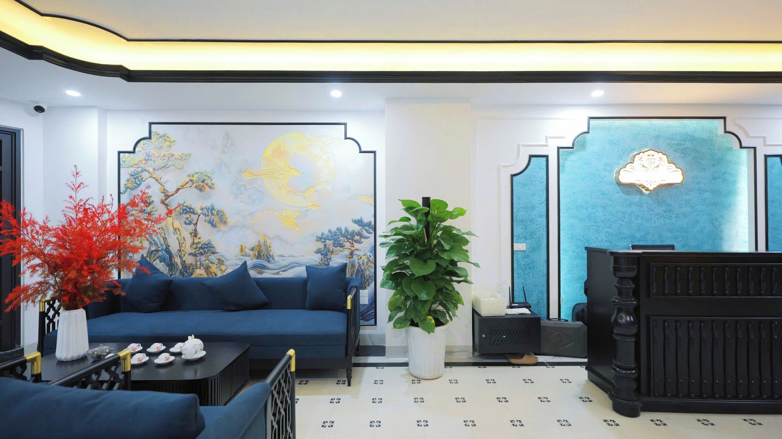 Un interior moderno con un sofá azul, un mural grande, un mostrador de recepción y una planta en maceta.