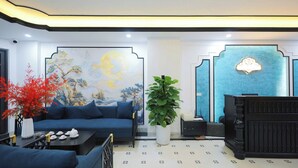 Un intérieur moderne avec un canapé bleu, une grande fresque murale, un comptoir d’accueil et une plante en pot.