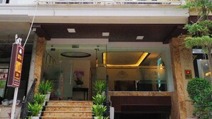 L’entrée d’un hôtel, avec une enseigne indiquant « ROYAL HOTEL » et un escalier menant à l’entrée.