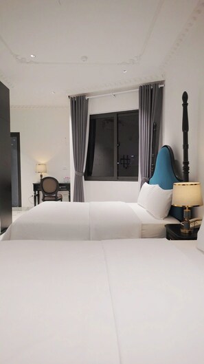 A hotel room with a large bed, a desk with a chair, a window with curtains, and a bedside table with a lamp. - Royal Hotel Trinh Van Bo Nam Tu Liem (Hanoi)