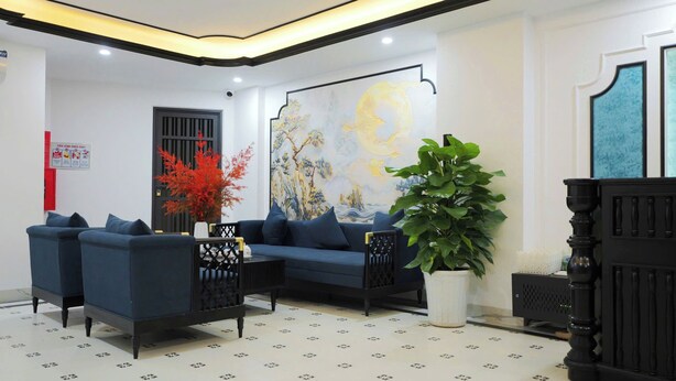 Un salon moderne avec un canapé bleu, un grand élément décoratif mural et une plante en pot.