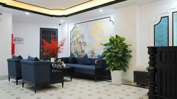 Un salon moderne avec un canapé bleu, un grand élément décoratif mural et une plante en pot.