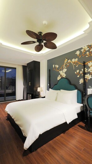 A hotel room with a large bed, a ceiling fan, a nightstand with a lamp, and a wall with a floral mural. - Royal Hotel Trinh Van Bo Nam Tu Liem (Hanoi)