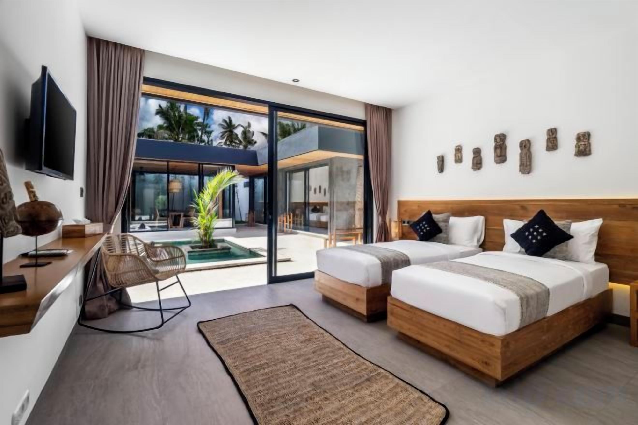 A modern hotel room with a large bed, a desk, a chair, and a view of the outdoor area.