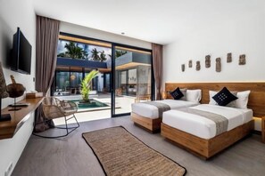 A modern hotel room with a large bed, a desk, a chair, and a view of the outdoor area. - Villa Maya Bay by BaliSuperHost (Bali)